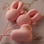 Close-up of the soft-touch pink silicone exterior and flexible wiring of the HH Deer intimate massager set against a decorative lifestyle background.