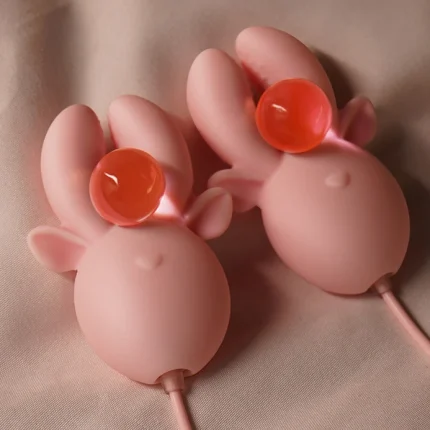 The dual antler-shaped stimulation heads of the Deer Clamp holding orange decorative spheres to illustrate the firm yet gentle grip of the pleasure device.