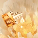 Close-up of a golden drop falling from the nozzle of the arousal oil bottle.