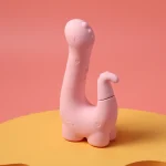 Side profile of the Little Dino pink silicone vibrator featuring a whimsical dinosaur-inspired design.