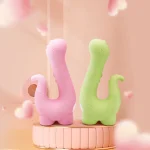 HH Little Dino adult toys displayed in Medium Pink and Grass Green colors on a decorative podium.