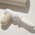 Portable personal massager lying on a textured surface for travel-ready wellness.