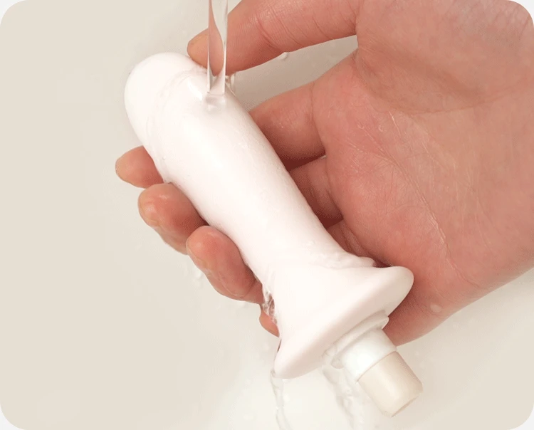 Waterproof body massager being rinsed under water for easy hygiene maintenance.