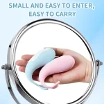 Lifestyle shot demonstrating the compact and travel-friendly size of the blue and pink whale massagers held in a palm.