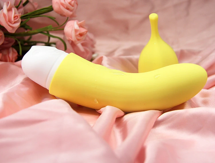 Ergonomic banana-shaped clitoral suction vibrator resting on pink silk fabric with floral accents, highlighting its playful and discreet aesthetic.