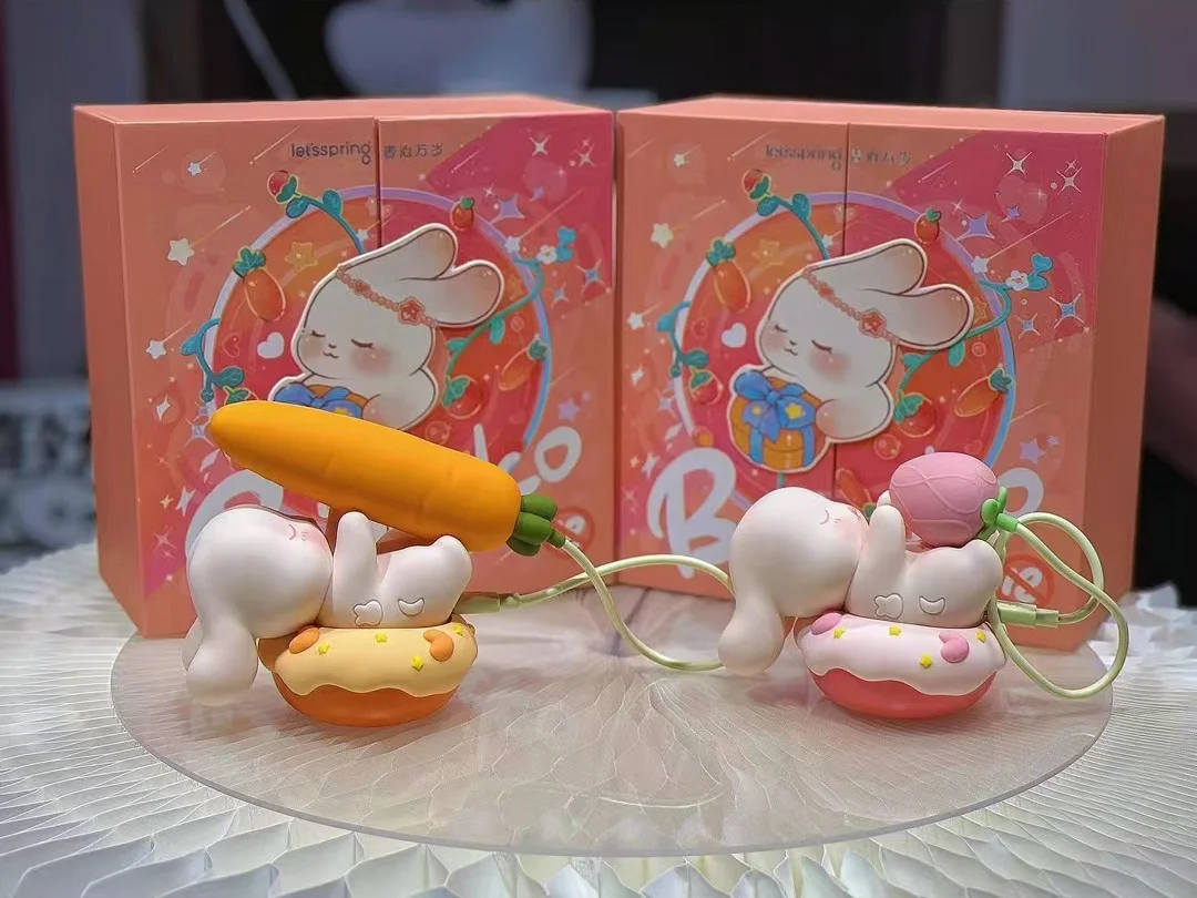 Product lineup of the Bubuko pleasure devices in orange and pink variations, displayed with their respective carrot and flower bud attachments on a retail stand.