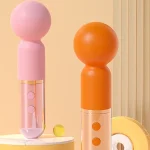 Comparison view of the HH Candy Massager in pink and orange standing on a modern marble display pedestal.