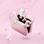 Lifestyle shot of the HH Candy Massager Mini floating out of a stylish pink handbag alongside cosmetics, highlighting its portable and travel-friendly nature.