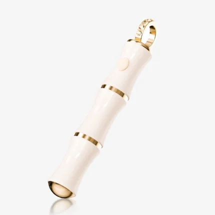 High-angle studio shot of a bamboo-shaped pleasure tool with gold bands and a crystal-inlaid loop.