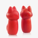 Close-up detail of two red fox-shaped massage candles highlighting the smooth texture and dual-wick placement on the ears.