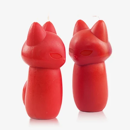 Close-up detail of two red fox-shaped massage candles highlighting the smooth texture and dual-wick placement on the ears.