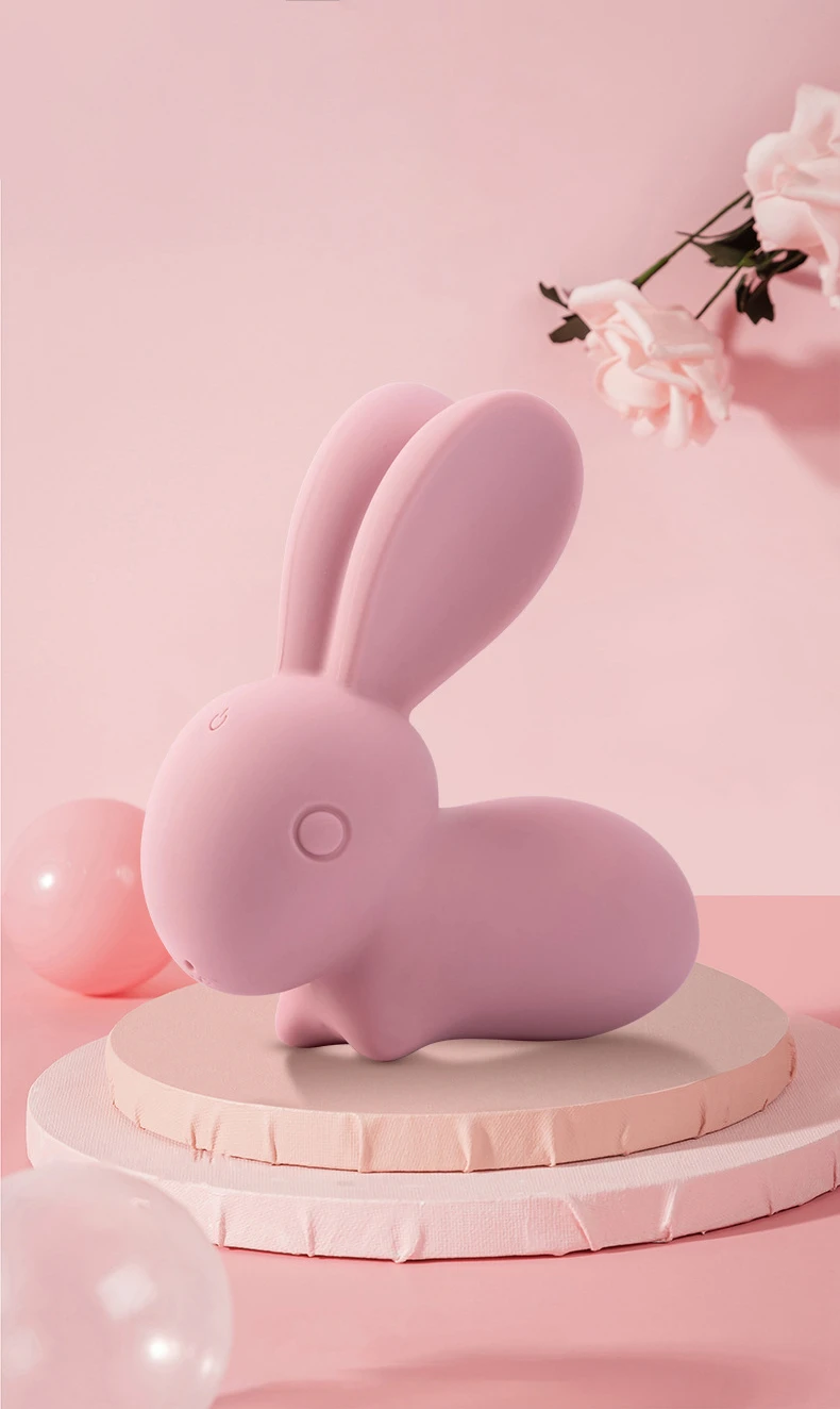Soft pink rabbit vibrator displayed on a decorative pedestal with floral accents, highlighting its aesthetic design as a lifestyle wellness product.
