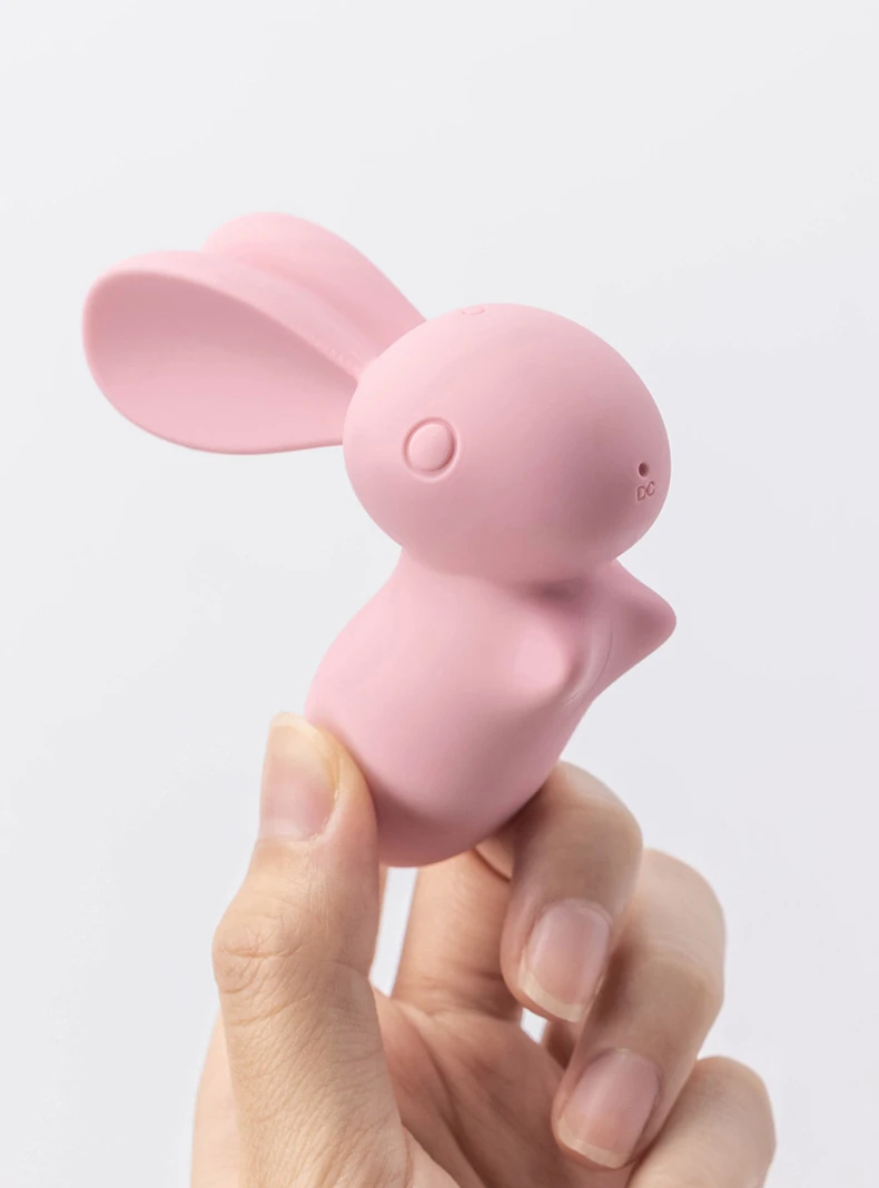 Close-up of a handheld pink bunny massager showing the DC charging port and the ergonomic, travel-friendly size of this personal pleasure device.