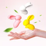 A hand holding three lightweight bunny stimulators with floating green leaves, illustrating the travel-friendly size and portable design of these adult products.