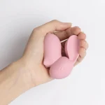 Scale shot of the compact pink bunny vibrator held in a palm to show its discreet, portable, and ergonomic shape for targeted stimulation.