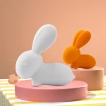 Vibrant orange and white bunny vibrators staged on decorative risers to showcase the playful color variety available for this intimacy device.
