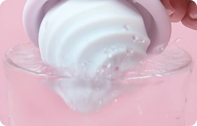 A high-grade silicone clitoral stimulator submerged in a glass of water to highlight its high-performance waterproof capabilities for bath or shower use.