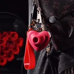 The heart-shaped wearable vibrator hanging as a stylish keychain on a luxury tote bag, demonstrating its travel-friendly and inconspicuous nature.