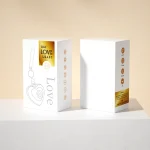 Discreet packaging for the intimacy tool, featuring a minimalist white gift box with gold foil lettering and icons detailing suction and vibration functions.