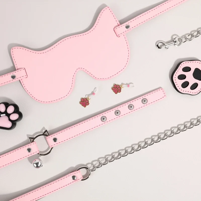 A complete pink kitty-themed intimacy set featuring a cat-ear blindfold, bell collar with leash, paw-print nipple clamps, and a decorative paw candle for sensory play.