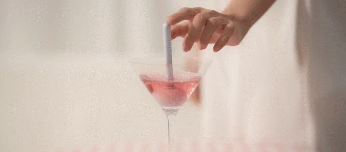 Lala Pop intimacy device being dipped into a cocktail glass to demonstrate its fully submersible IPX7 waterproof rating.