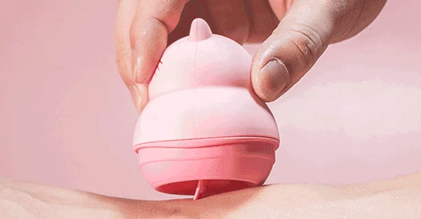 Close-up of the pink Licking Cat clitoral stimulator being used against skin to demonstrate its soft, medical-grade silicone texture.