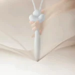 Lifestyle shot of a user holding the HH Loom through sheer fabric demonstrating the discreet and portable size of the pleasure tool.