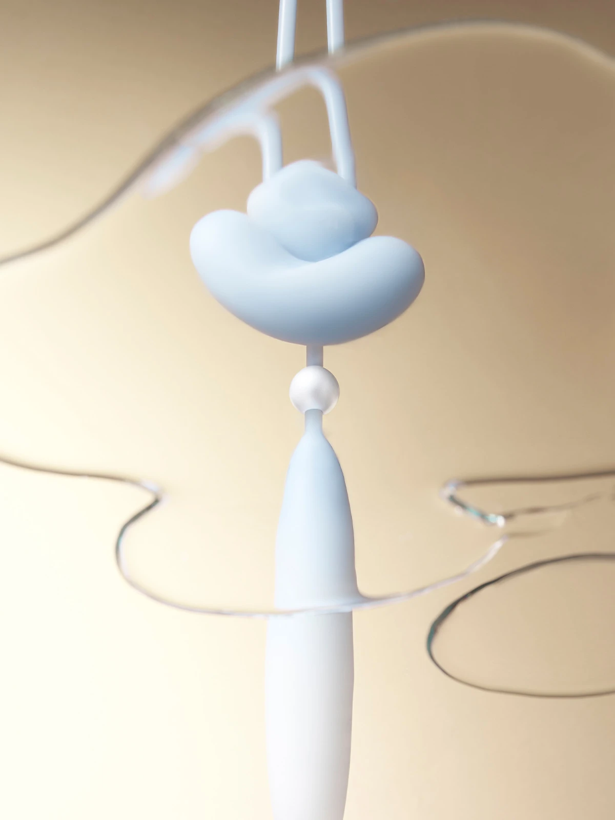 Artistic product shot of the baby blue HH Loom waterproof massager submerged in clear liquid to demonstrate splashproof durability.