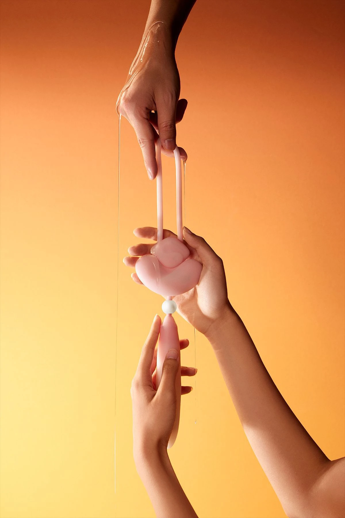 Hands holding the HH Loom silicone vibrator under a stream of clear gel to emphasize its use with water-based lubricants.