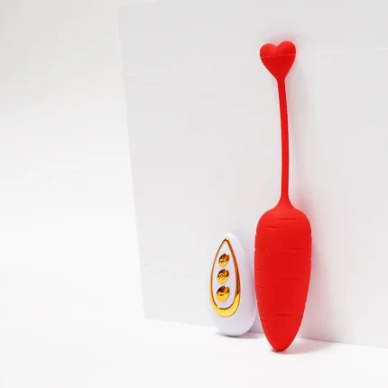 Minimalist lifestyle shot of the crimson red carrot stimulator with its elegant gold and white wireless remote control.