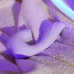 Close-up of the Moon Bud intimacy device with soft-touch medical silicone texture placed on a plush white towel.