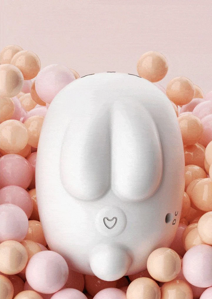 Top-down view of the HH Moon Rabbit vibrator's rabbit-ear design and heart-shaped power button nestled among soft pastel aesthetic beads.