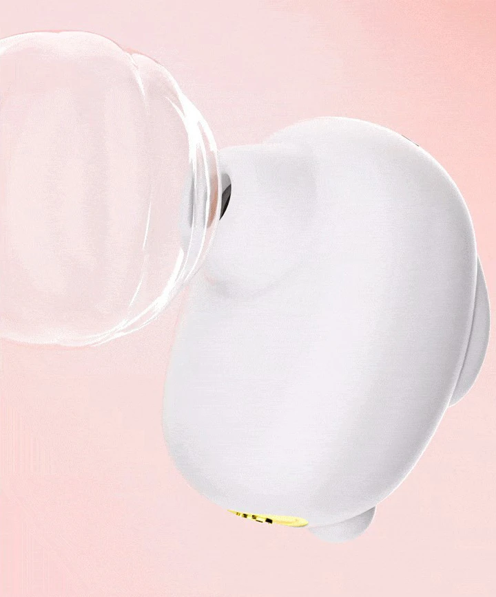 Close-up side profile of the white silicone suction toy showing the sleek, rounded body and gold-accented base against a soft pink background.