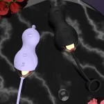 Luxury lifestyle display of the lavender and black Neko Elven intimacy tools on a dark marble surface with red roses.