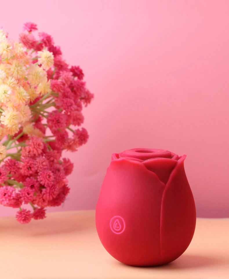 The Rose Desire suction toy standing upright against a soft pink background with floral accents, emphasizing its elegant and discreet design.