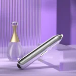 Lifestyle composition of a sleek silver massage wand displayed next to a designer perfume bottle on a contemporary purple glass shelf.