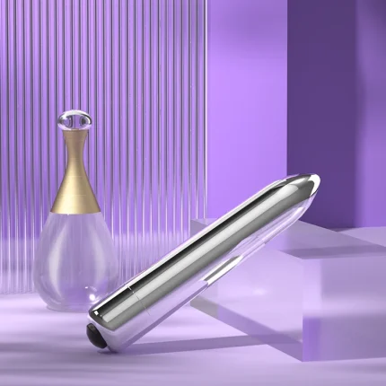 Lifestyle composition of a sleek silver massage wand displayed next to a designer perfume bottle on a contemporary purple glass shelf.