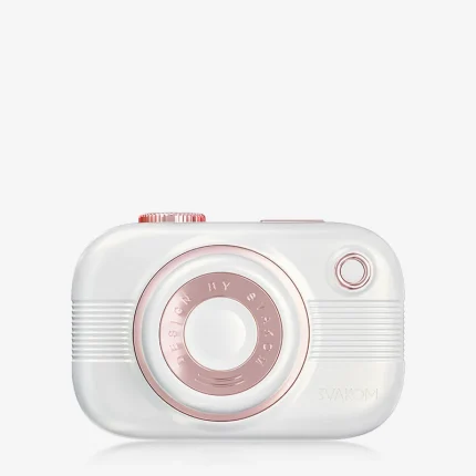 Perspective view of a white travel-friendly air-pulse stimulator, showcasing the ergonomic "lens" nozzle and the textured power buttons located on the top of the device.