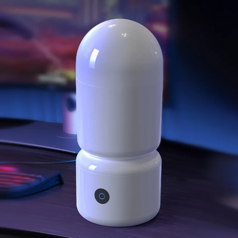 Discreet lifestyle shot of a modern white stroker device placed on a wooden desk next to a gaming setup.