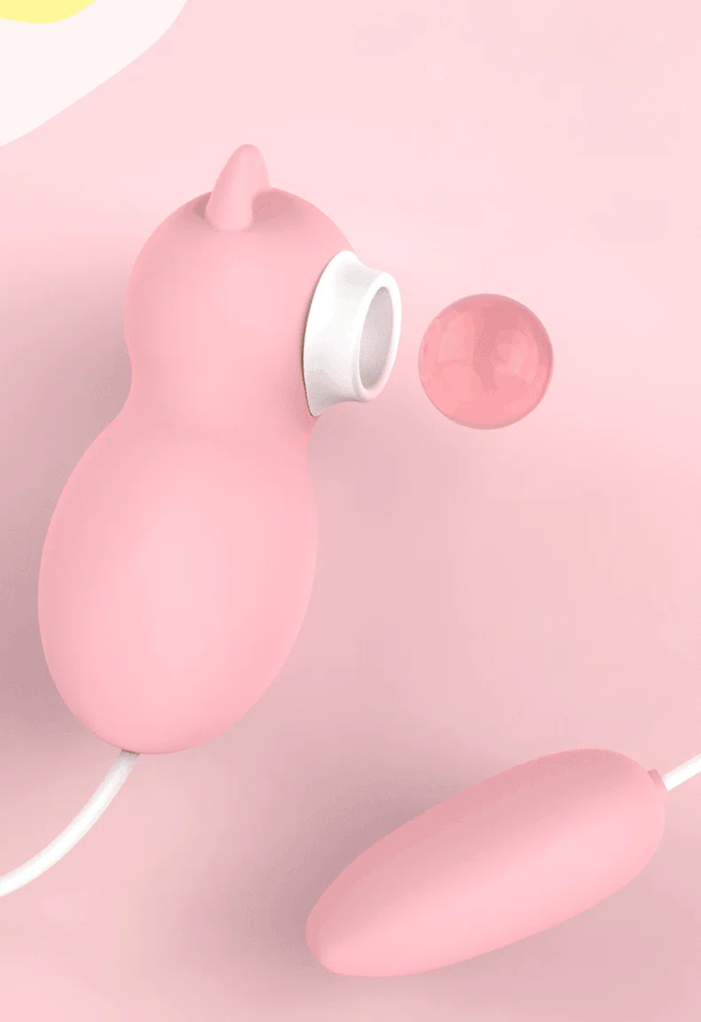 Side profile of the pink kitten-shaped clitoral stimulator featuring a soft silicone suction nozzle and accompanying egg vibrator.