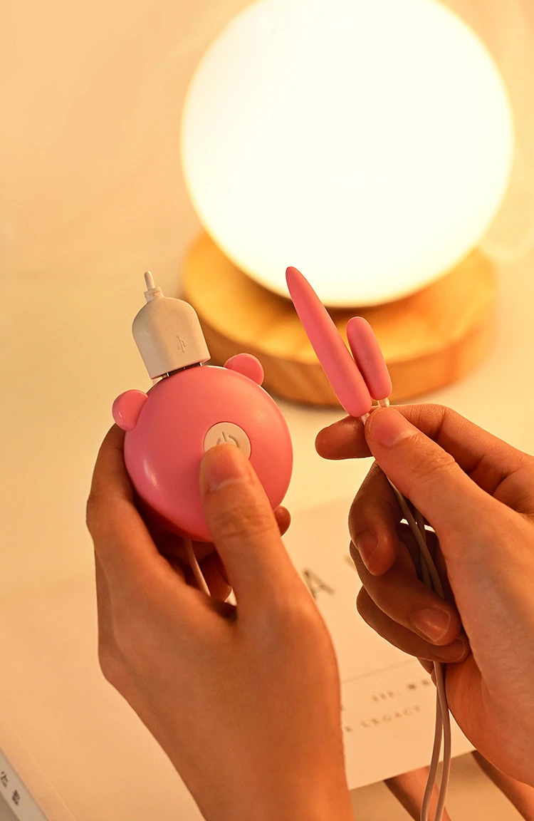 A person holding the HH Tiny Fingertip Vibrator, showcasing the compact, palm-sized controller and the different sizes of the two precision stimulation heads.