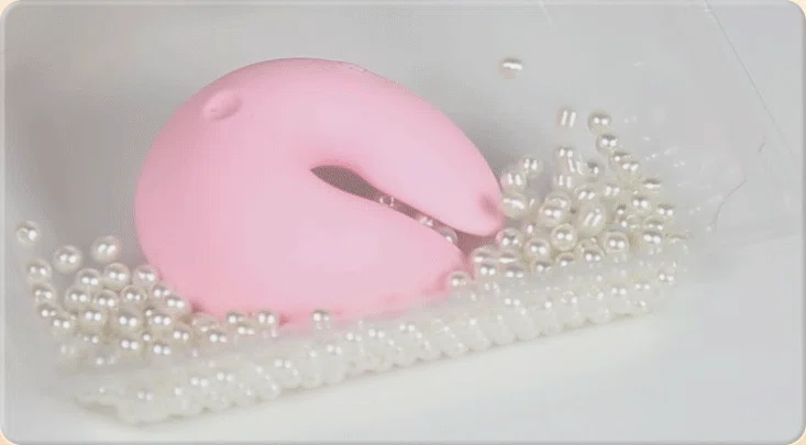 HH pink silicone nipple vibrator displayed among elegant pearls to showcase luxury aesthetic.