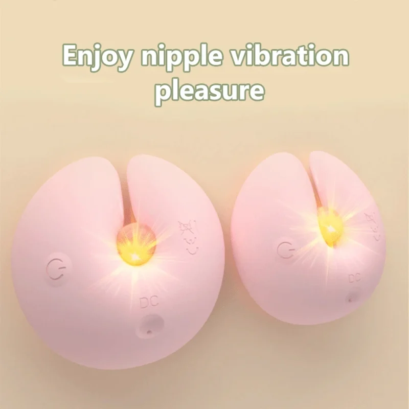 Pair of pink wearable nipple vibrators with glowing LED indicators showing active vibration modes for dual-point stimulation.
