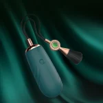 Lifestyle product shot of the teal vibrating wand resting against a dark green silk fabric background for a premium feel.