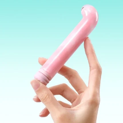 Curved pink G-spot vibrator held in hand against blue background