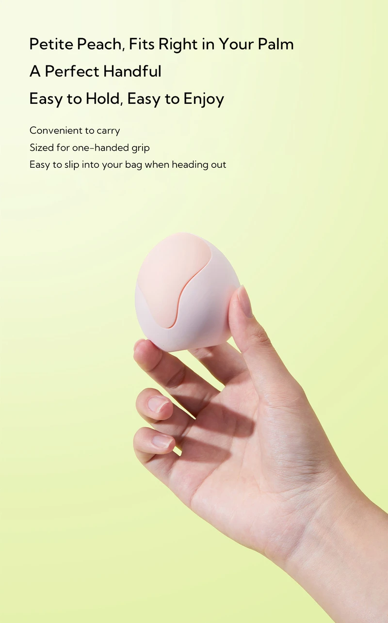 Hand holding compact peach-shaped clitoral vibrator sized to fit in palm