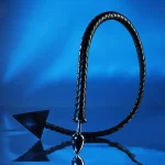 Black braided leather devil tail plug standing upright on reflective blue surface