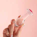 clear glass anal plug with pink jewel base held between fingers Discreet Sex Toys Brand - HooHss