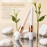 Slim beginner vibrator with rose gold accents displayed among stones and white flowers Discreet Sex Toys Brand - HooHss